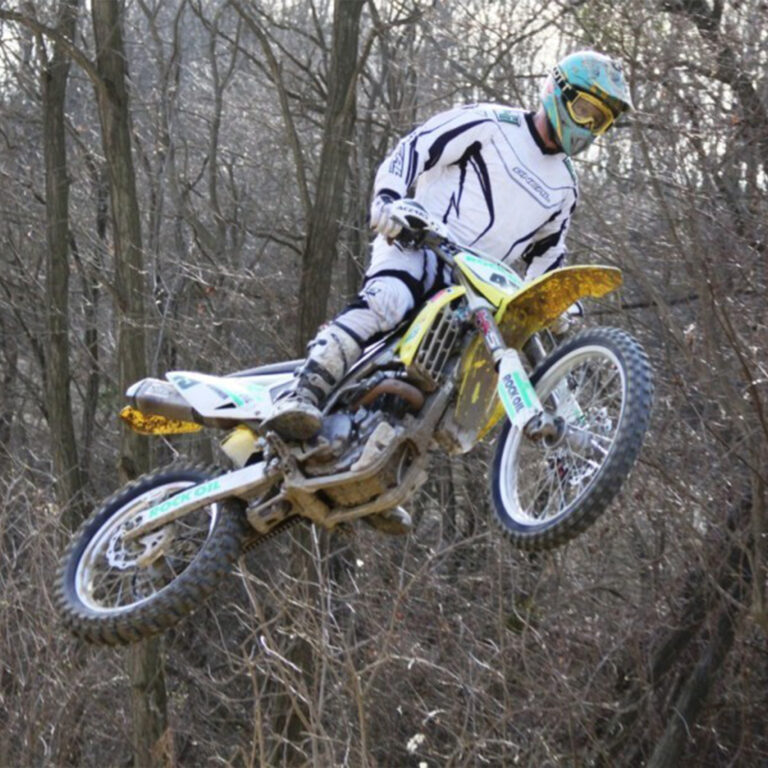 Mike Wohner auf Suzuki RMZ 450 im SPrung mit Bäumen im Hintergrund.